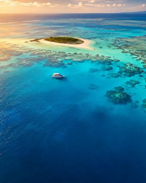 Aerial view of a reef, sand cay and boat in turquoise water