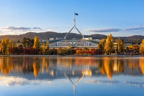 Parliament House in Canberra reflected in Lake Burley Griffin with autumn trees