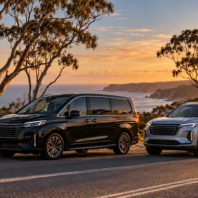 A black people-mover and a silver SUV parked on a coastal road at sunset